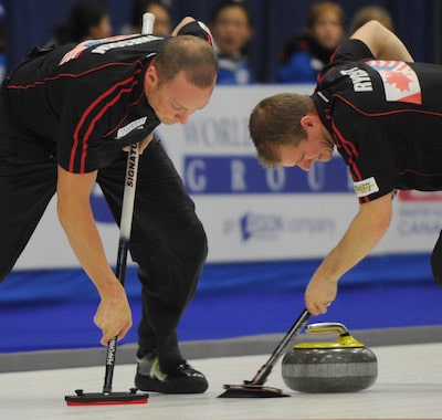 Nolan Thiessen, left, and Carter Rycroft scrub a rock during the 2011 World Financial Group Continental Cup in St. Alberta, Alta. (Photo CCA/Michael Burns)