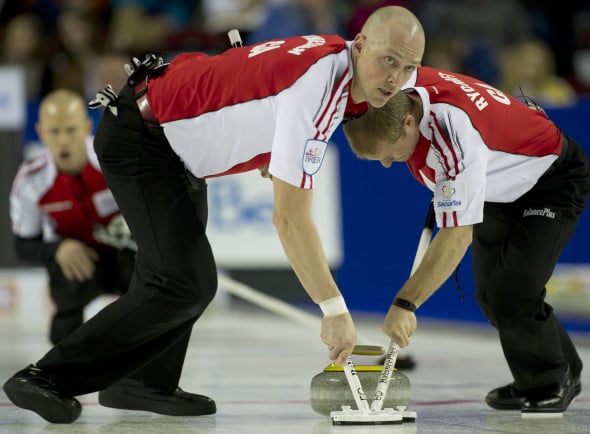 Nolan Thiessen, left, and Carter Rycroft sweep Pat Simmons' rock during the 2015 Tim Hortons Brier in Calgary. (Photo, Curling Canada/Michael Burns)