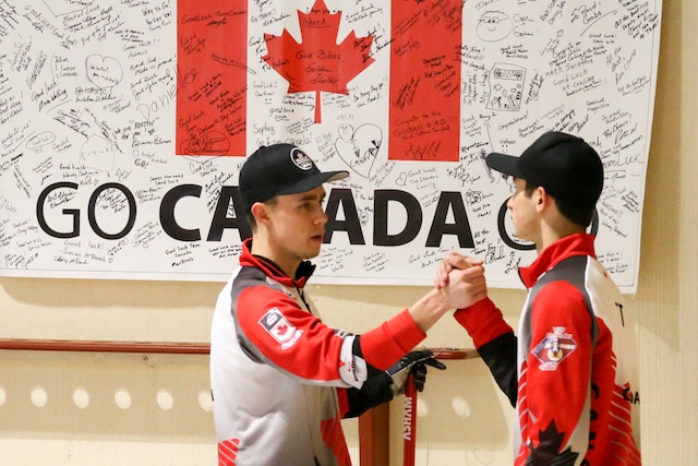 Team Canada's Kyle Doering and Colton Lott celebrate in front of the Canadian flag at the Taarnby Curling Club during the 2016 World Junior Curling Championships (WCF/Richard Gray)