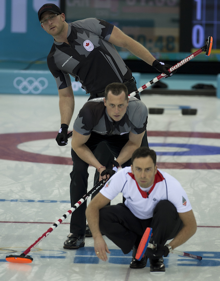 Great Britain skip David Murdoch checks out his shot with Canada's Ryan Harnden, top, and E.J. Harnden looking on.