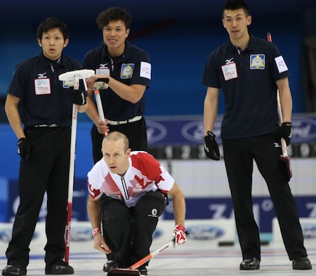 Canadian third Pat Simmons delivers his rock as Japanese players look on. (Photo, World Curling Federation/Richard Gray)
