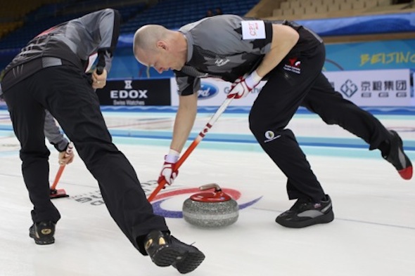 Team Canada sweepers Nolan Thiessen, right, and Carter Rycroft work on a rock during Monday's win. (Photo, World Curling Federation/Richard Gray)