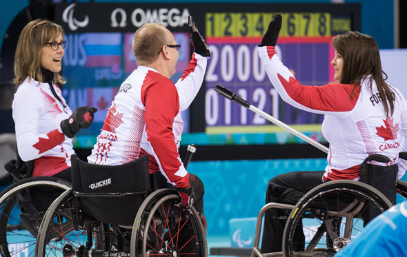 Sochi, RUSSIA - Mar 15 2014 - Sonja Gaudet, Dennis Thiessen and Ina Forrest give each other high waives as Canada takes on Russia in the Gold Medal Wheechair Curling match at the 2014 Paralympic Winter Games in Sochi, Russia.  (Photo: Matthew Murnaghan/Canadian Paralympic Committee)
